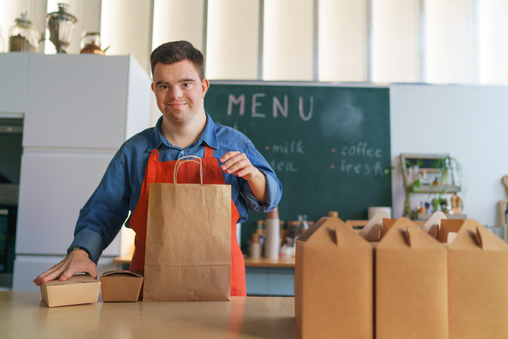 young Down Syndrome waiter working in take away restaurant, social inclusion